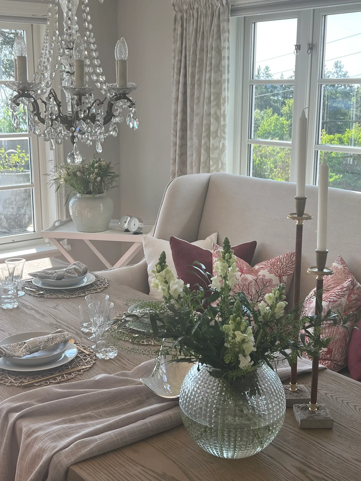 Dekket spisebord med blomster, lysestaker og krystallkrone
