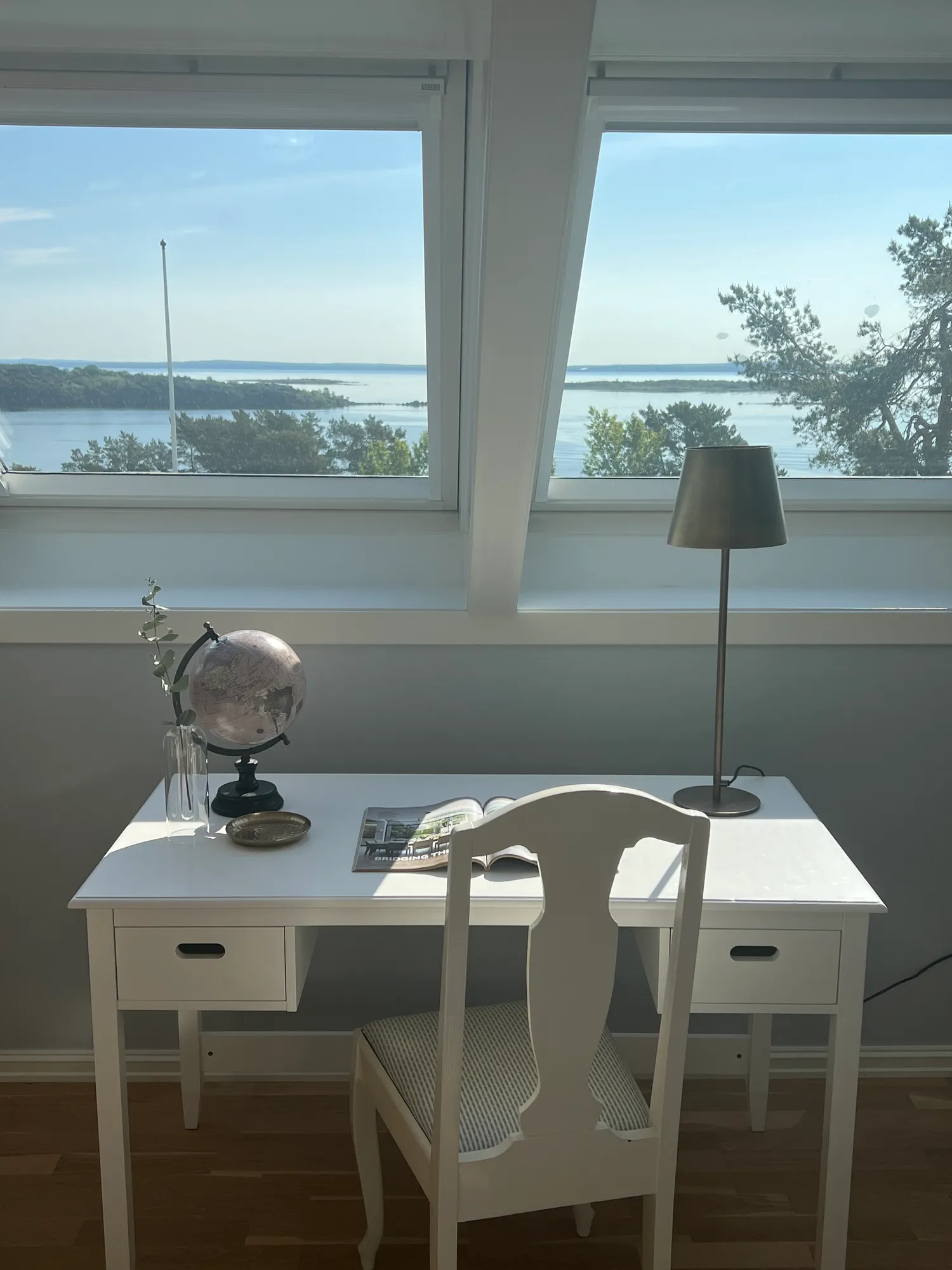 Hvitt skrivebord under takvinduer med utsikt over fjorden