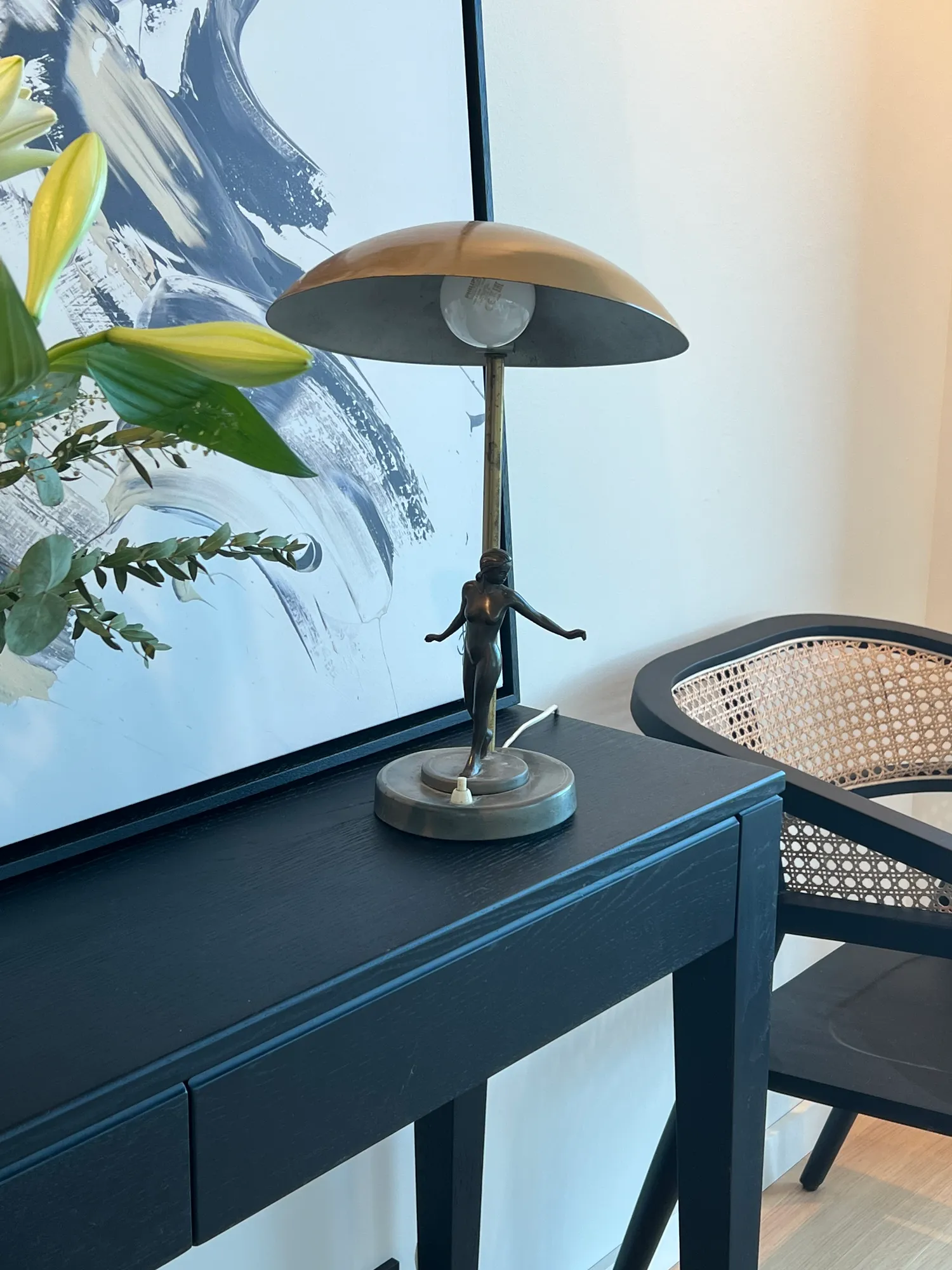 Bordlampe i messing og liljer på det sorte konsollbordet