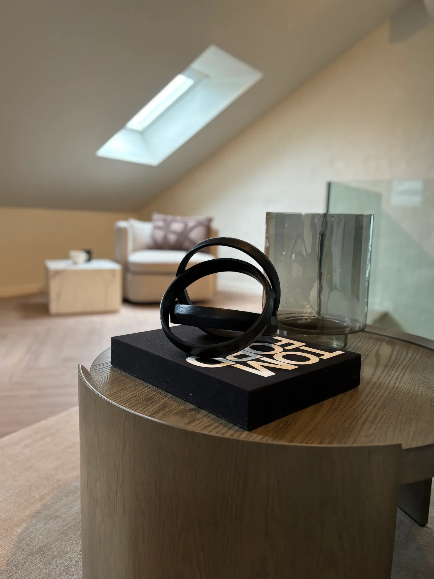 Sort skulptur og glassvase på rundt sidebord i loftstuen