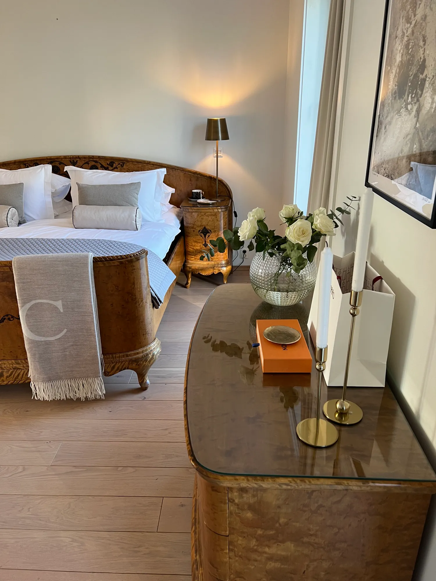 Soverom med antikk seng og kommode med blomster og lysestaker