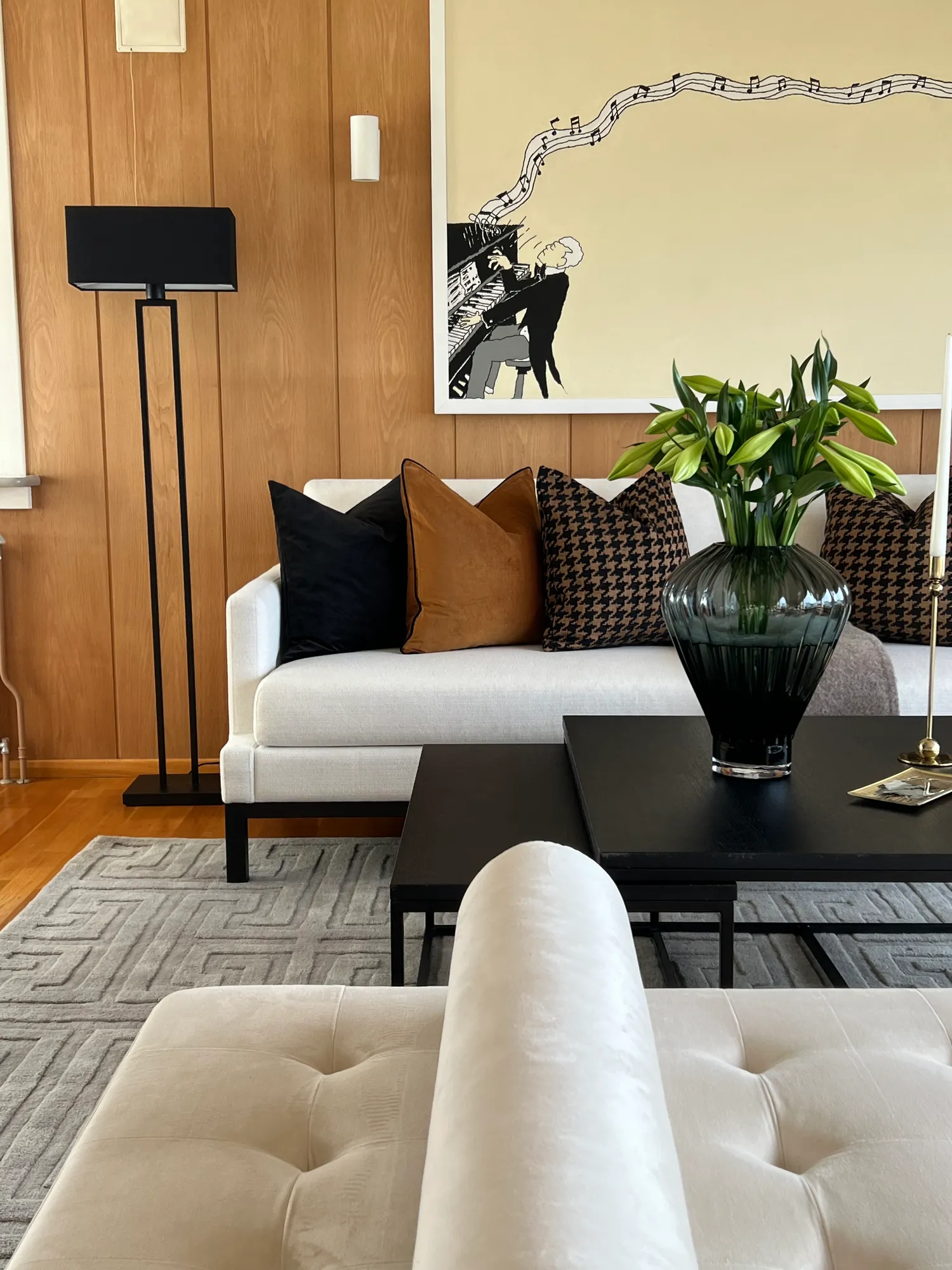 Sofa og daybed foran eikepanel med sort gulvlampe